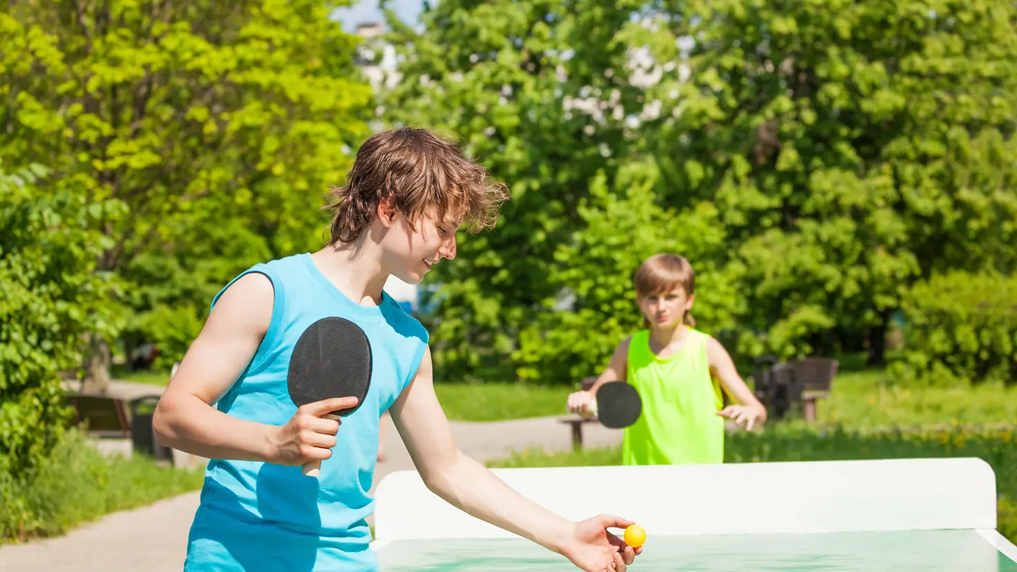 Das Bild zeigt zwei Jungs beim Tischtennis spielen.