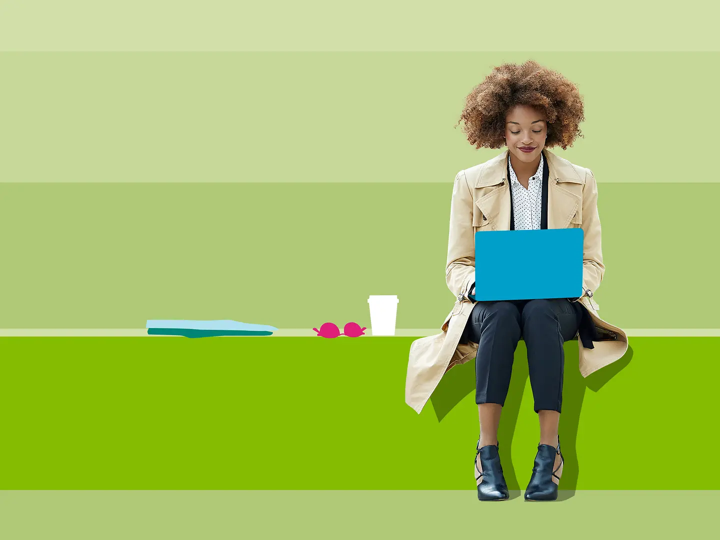 Eine Frau sitzt vor einem grünen Hintergrund und schaut auf ihren Laptop. 