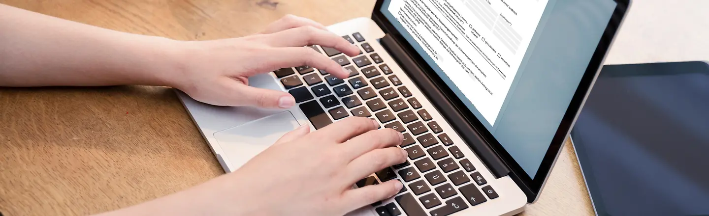 Eine Person füllt online ein Formular am Laptop aus