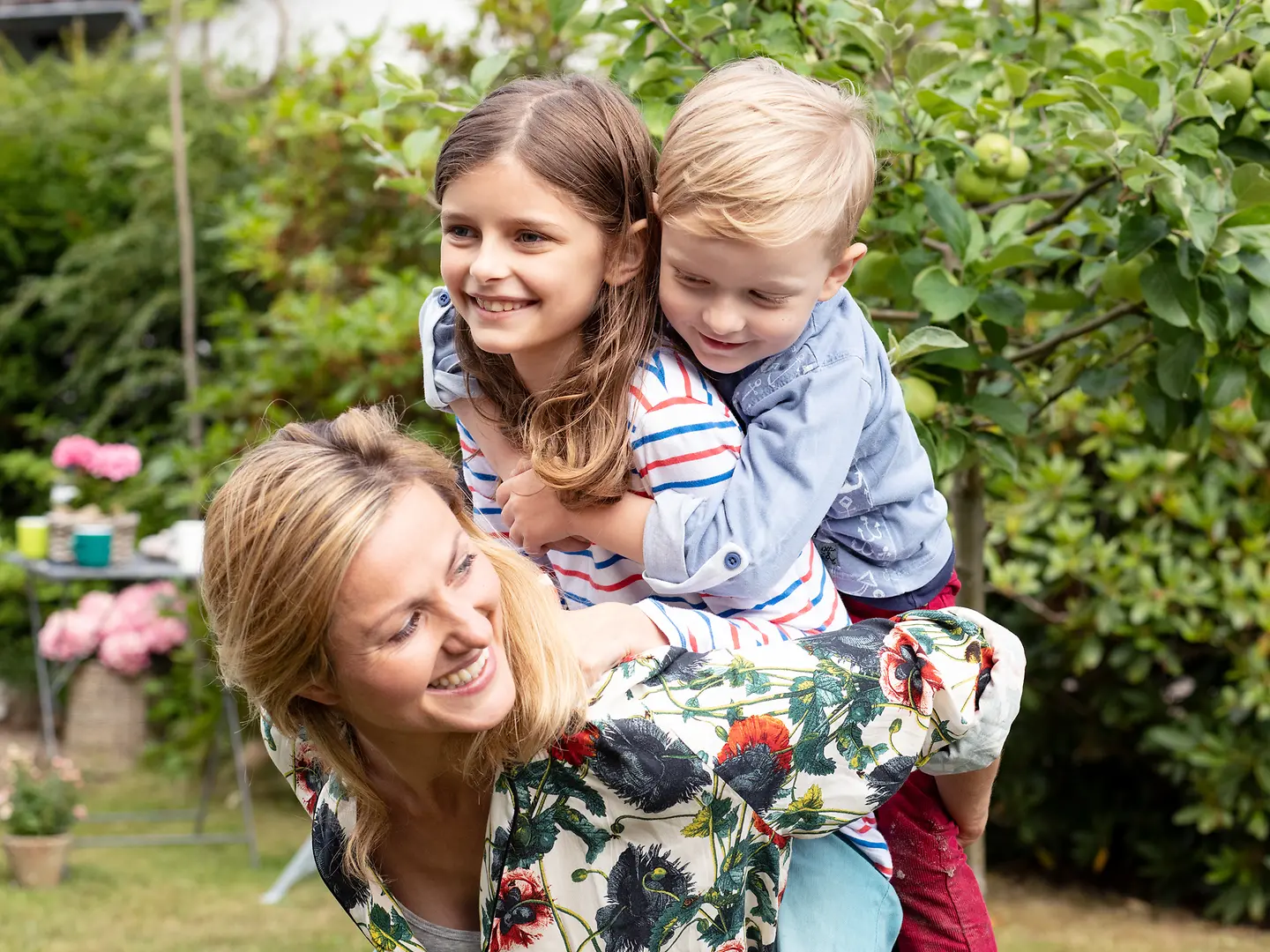 Eine Mutter tobt mit ihrer Tochter und ihrem Sohn im Garten