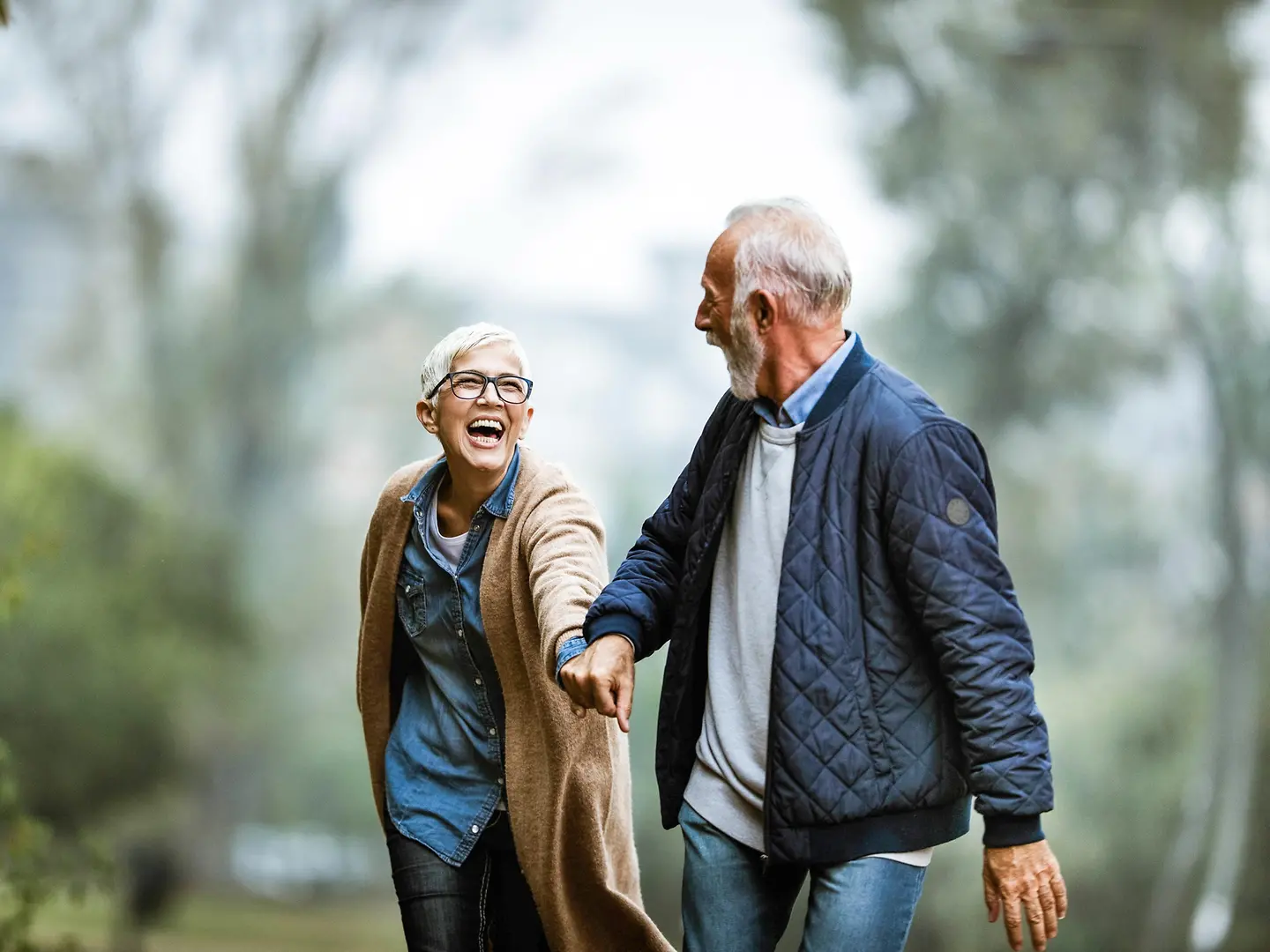 Seniorenpaar lachend beim Spaziergang im Wald.