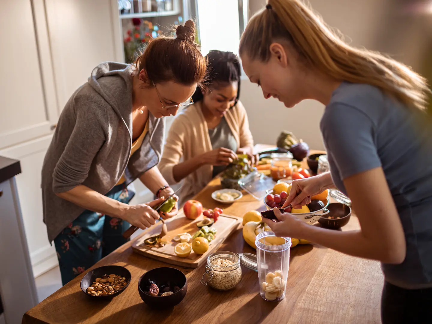 Drei junge Frauen kochen zusammen vor und machen Meal Prep,