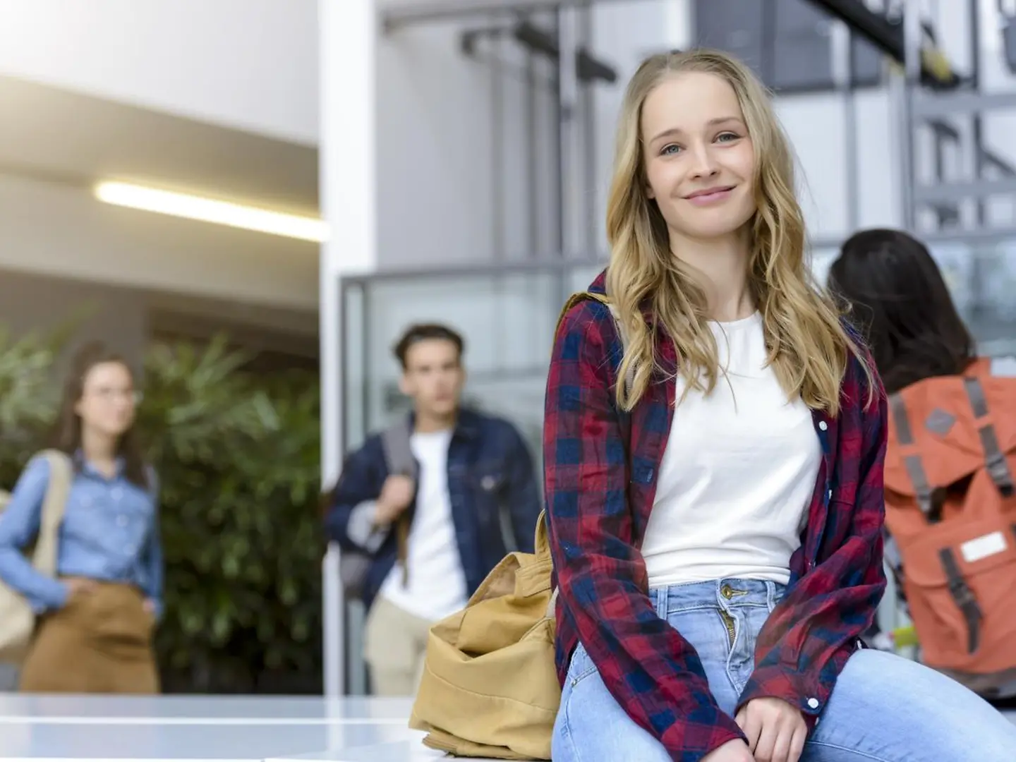 Zu sehen ist ein Mädchen, das vor einer Schule sitzt 