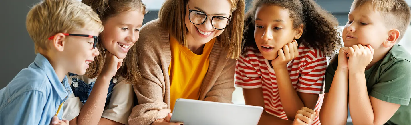 Zu sehen sind Kinder am Tisch mit einer Frau 