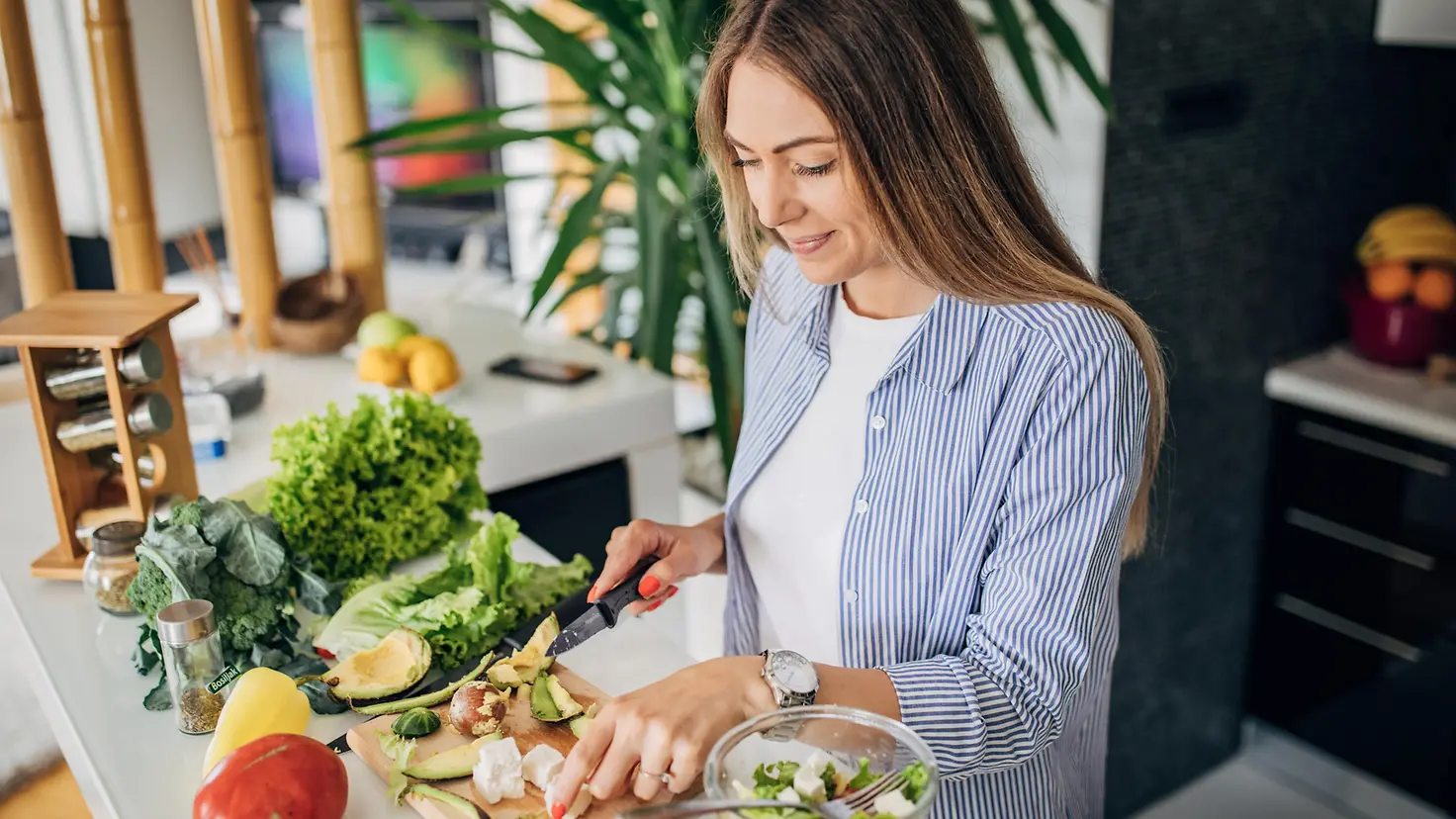 Eine junge Frau bereitet sich einen gesunden Salat zu