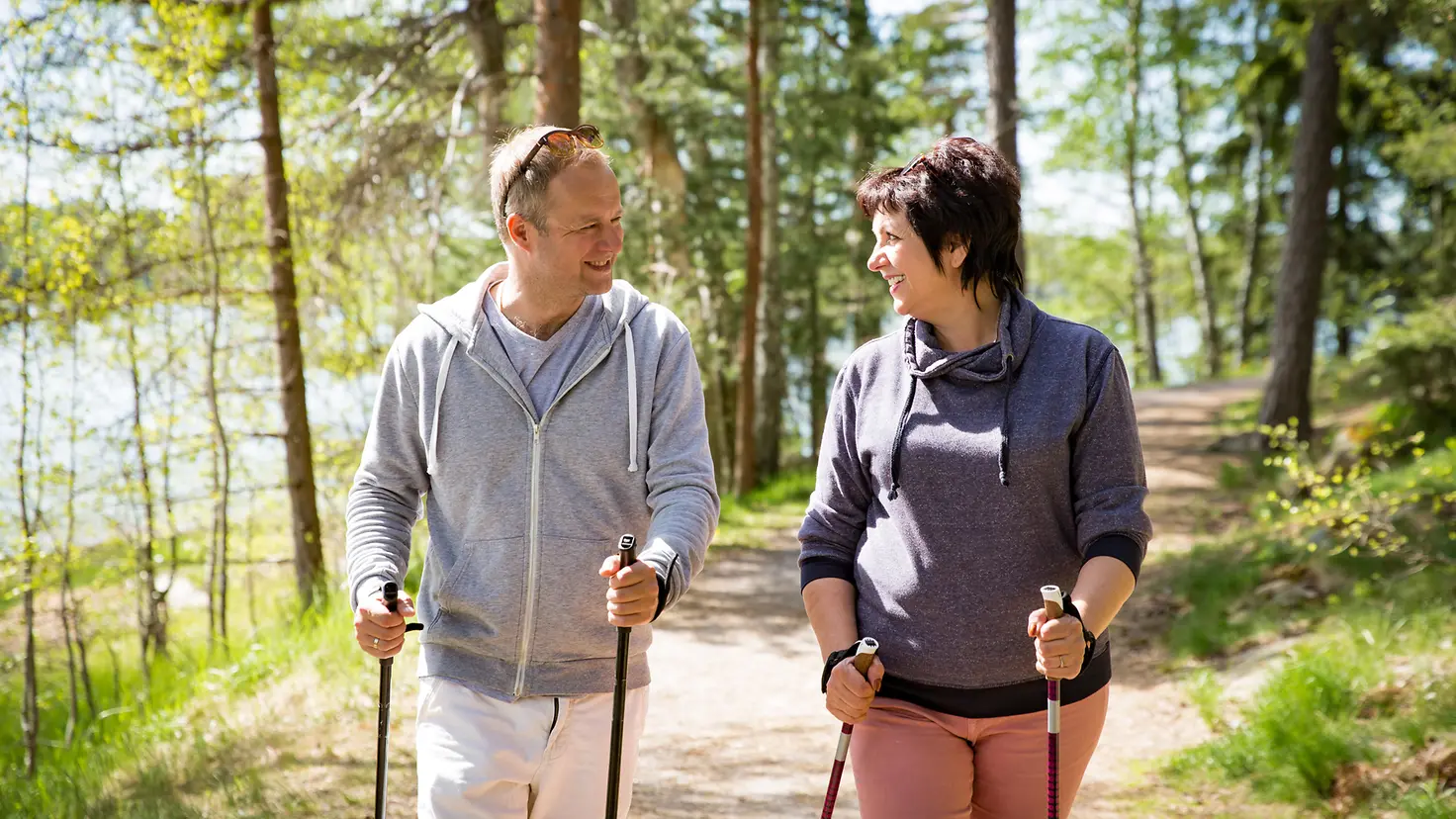 Zu sehen sind ein Mann und eine Frau beim Nordic Walking im Wald