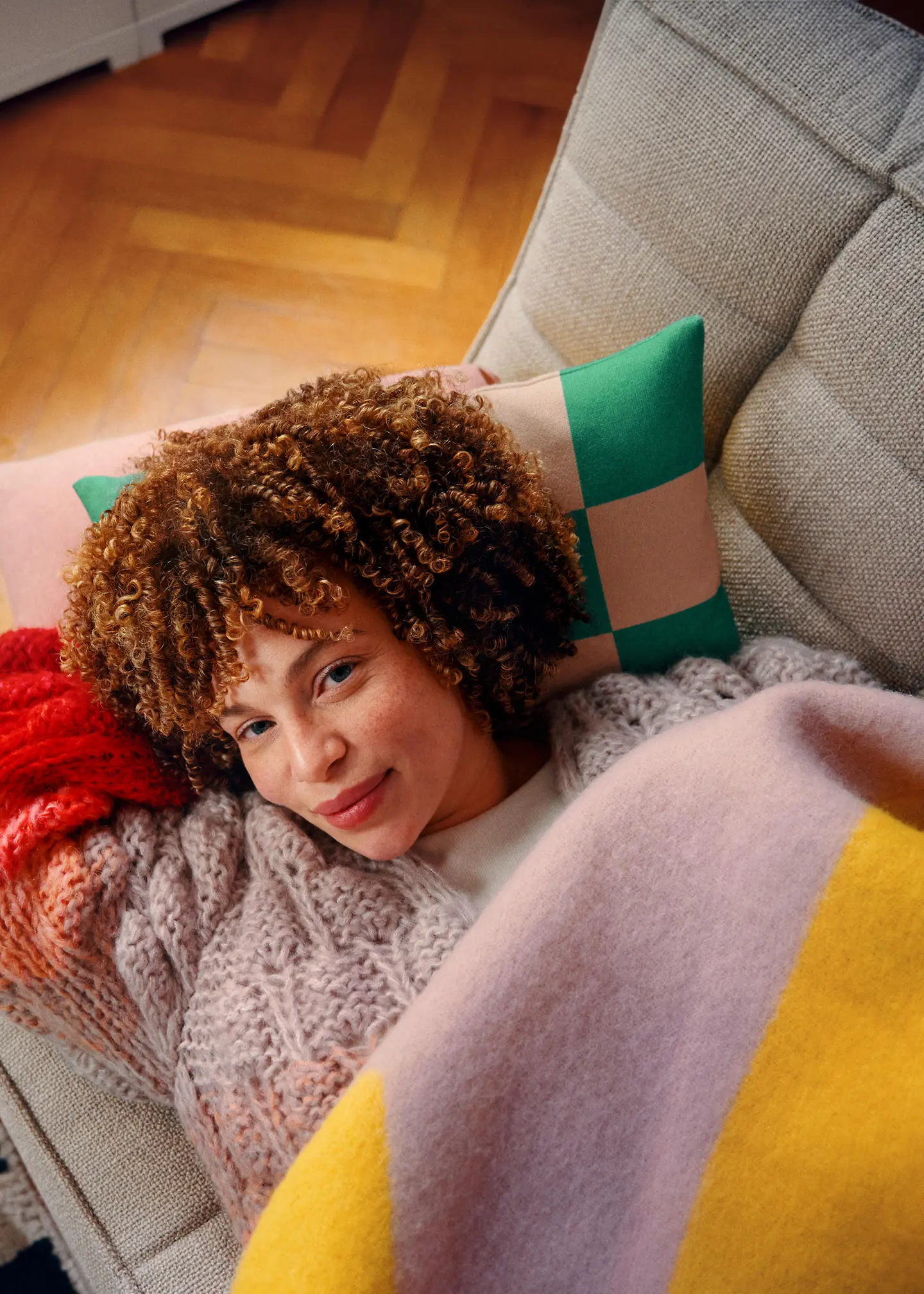 Eine Frau liegt angeschlagen auf ihrem Sofa. 