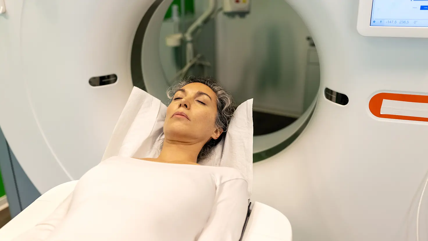 Eine Frau auf einer Therapieliege erhält eine Computertomografie (CT) am Kopf.