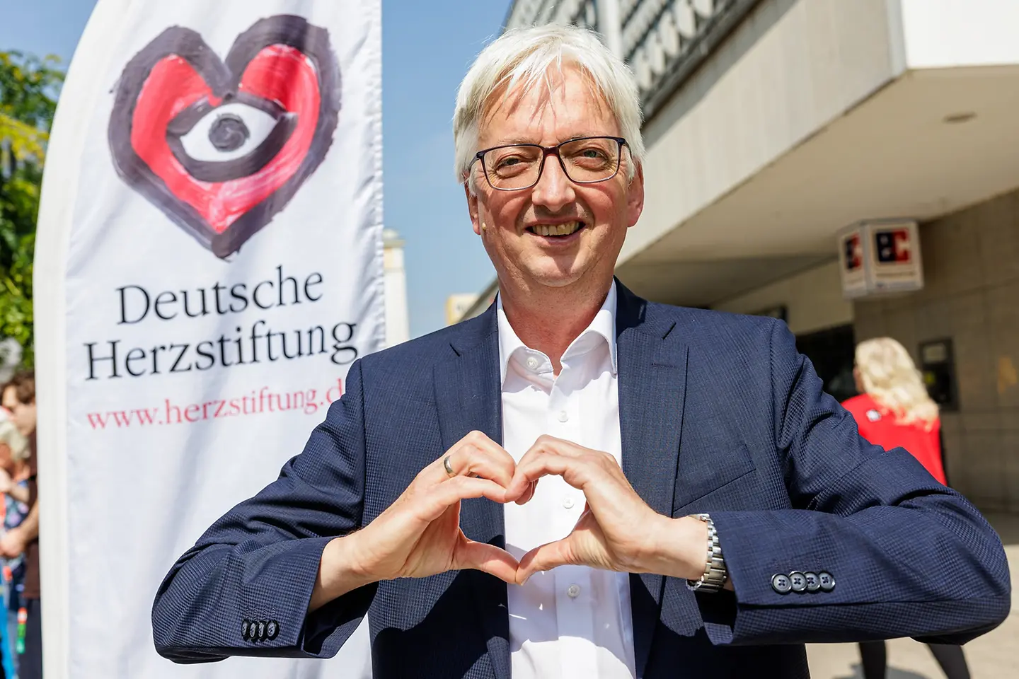 Staatssekretär Wolfgang Beck formt mit seinen Händen ein Herz.