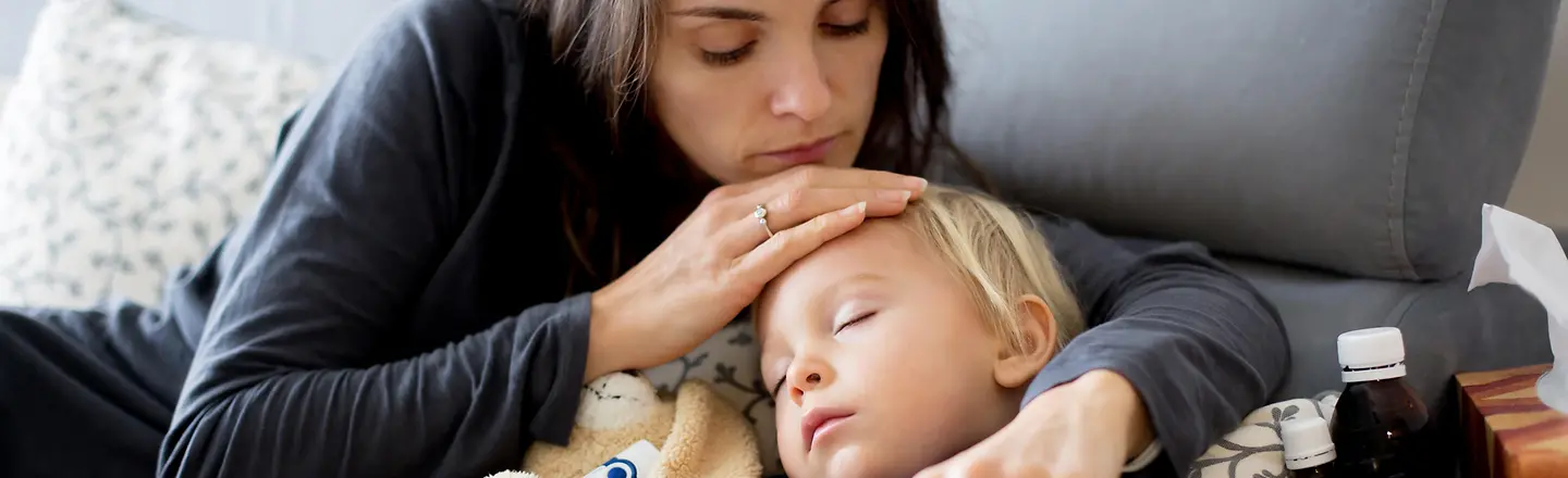 Zu sehen ist eine Mutter, die ihre rechte Hand auf die Stirn des kranken Kindes legt.