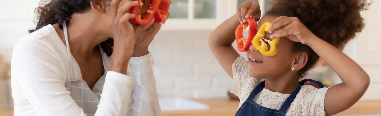 Eine Mutter schneidet mit ihrer Tochter Paprika in Scheiben 