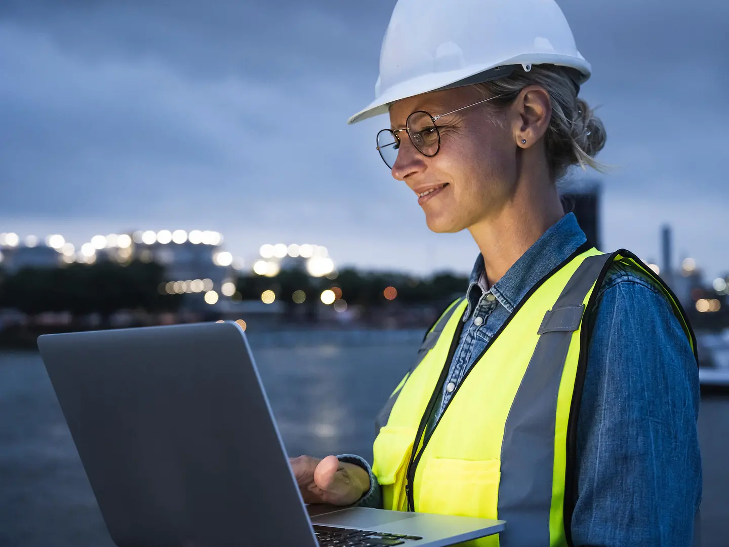 Eine Frau mit Helm und Schutzweste arbeitet nachts auf der Baustelle