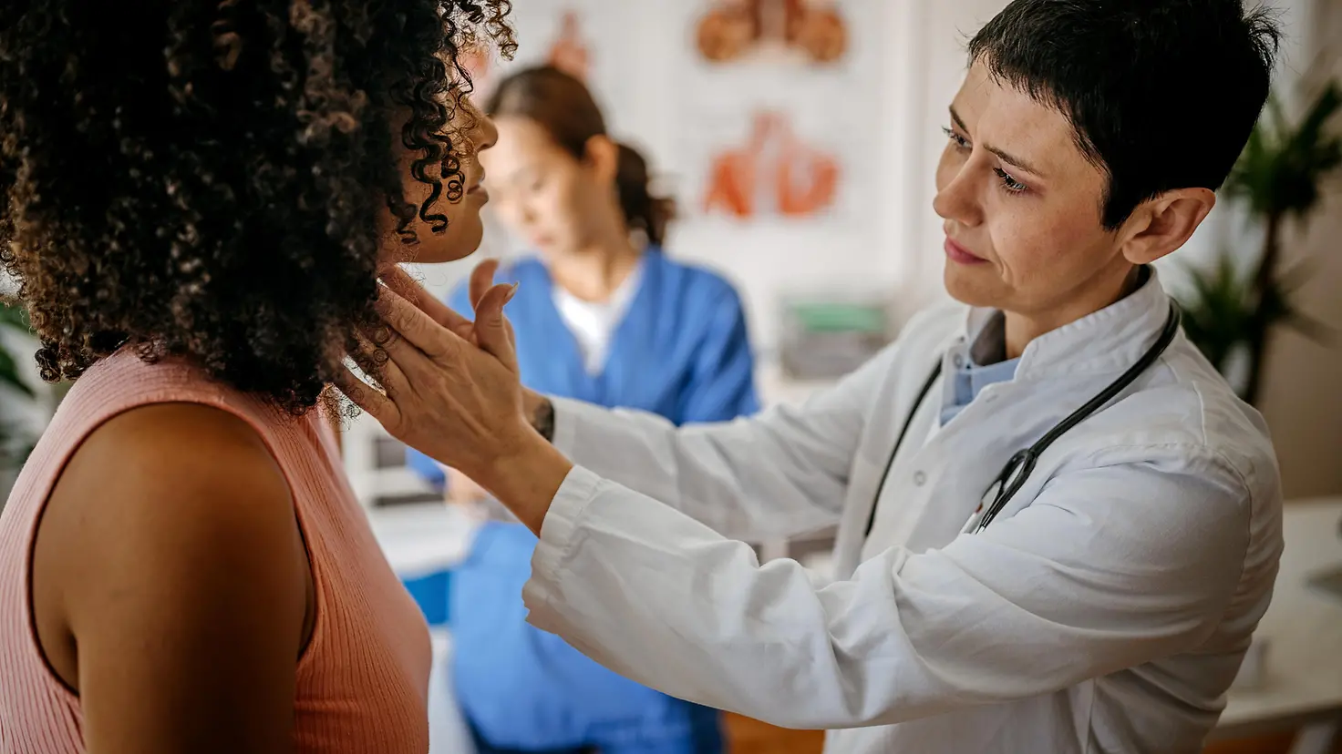 Ärztin untersucht Haut an der Schulter einer Patientin mit einer Lupe