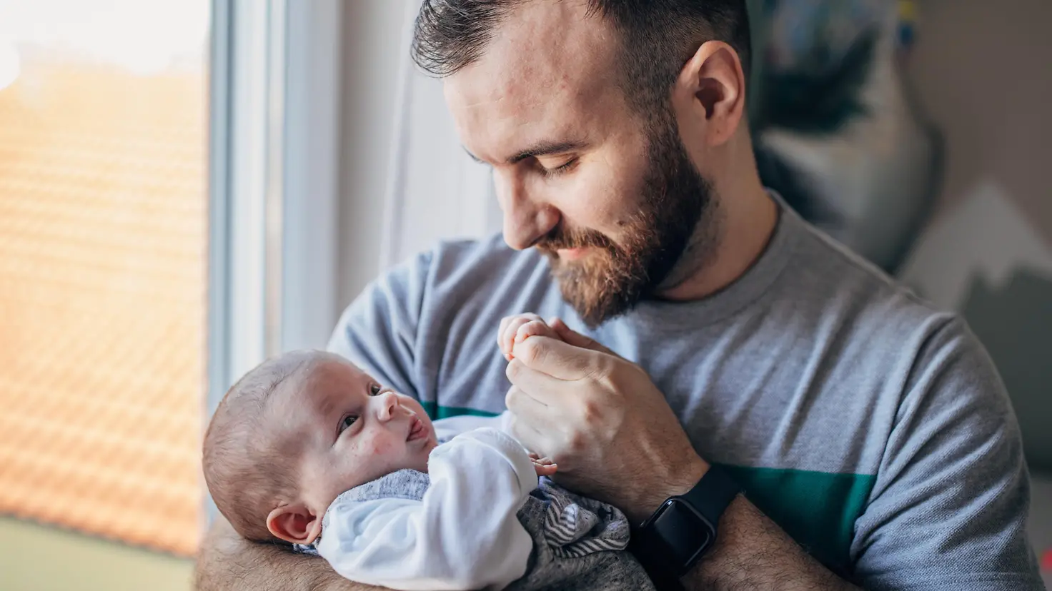 Vater hält seinen kleinen Jungen - ein Baby - zu Hause in den Armen