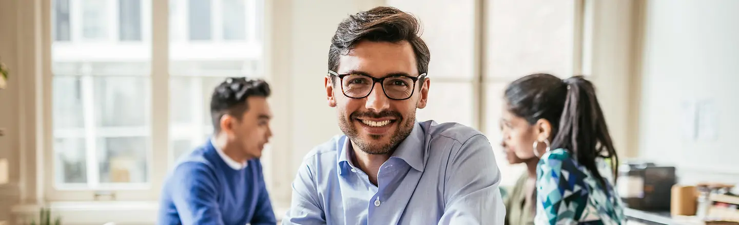 Ein Team junger Mitarbeitender sitzt um einen Besprechungstisch