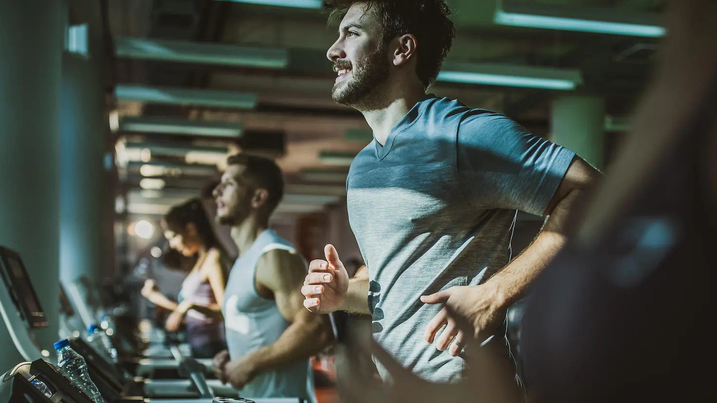 Junge Männer laufen im Fitnessstudio auf dem Laufbahn