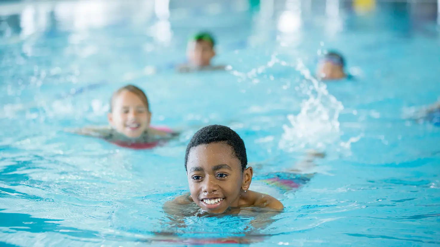 Kinder schwimmen beim Schwimmunterricht Bahnen.